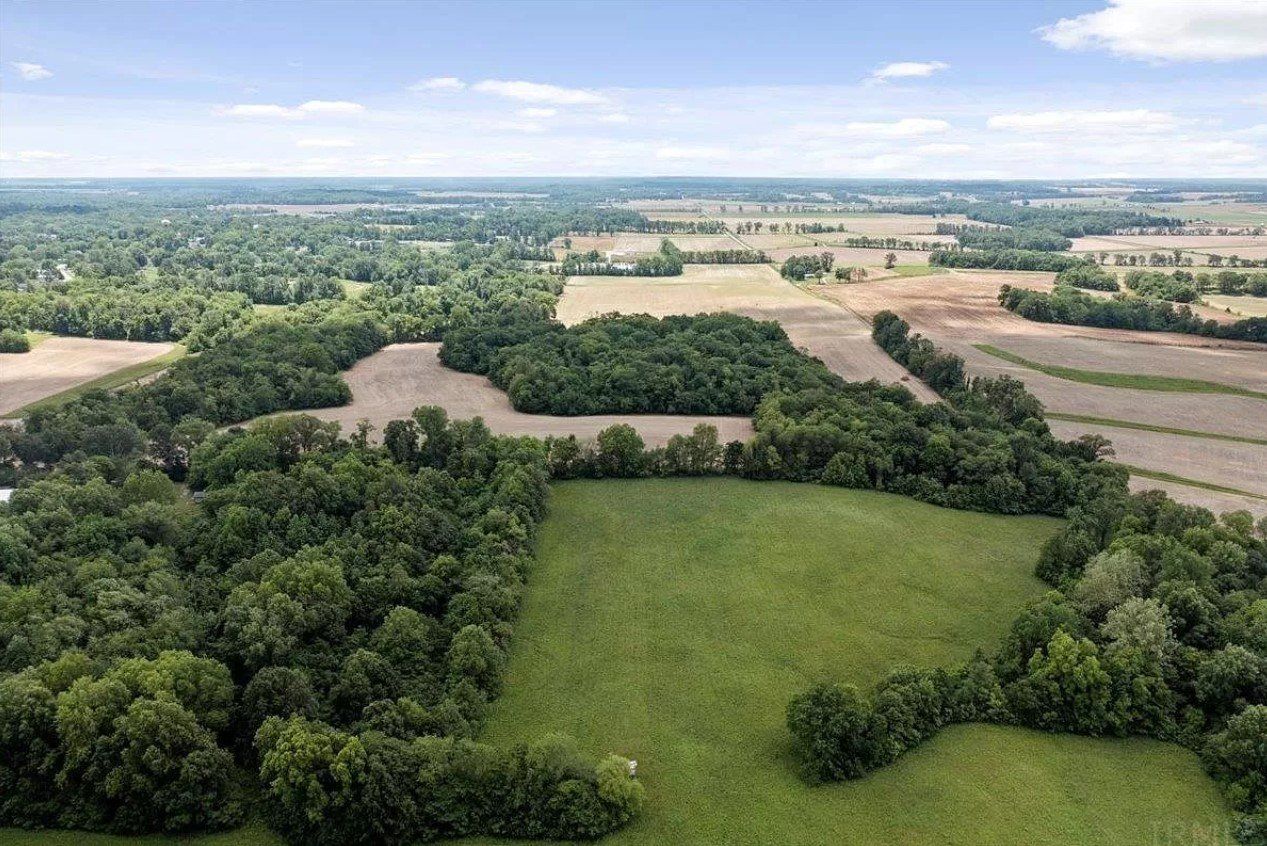 An aerial view of a lush green field surrounded by trees and fields.
