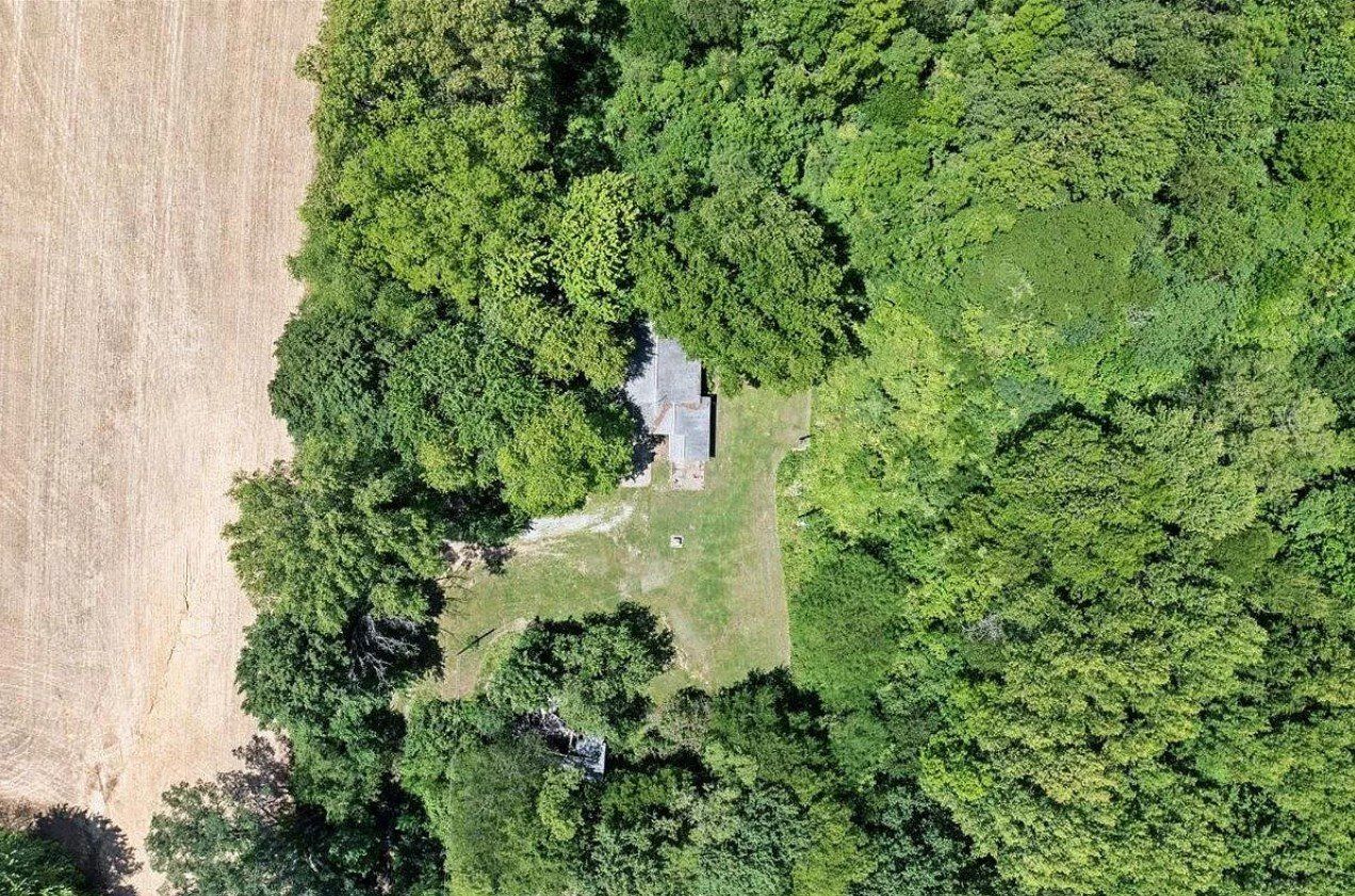 An aerial view of a house surrounded by trees and a field.