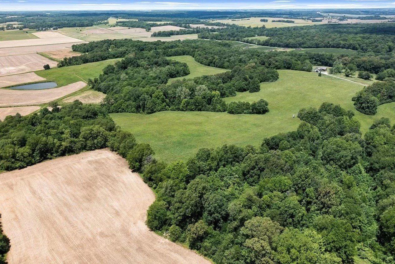 An aerial view of a lush green field surrounded by trees and fields.