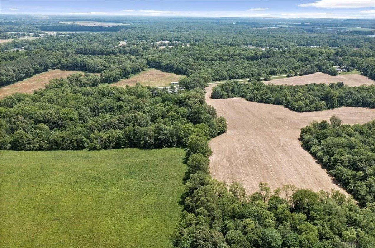 An aerial view of a field surrounded by trees and fields.