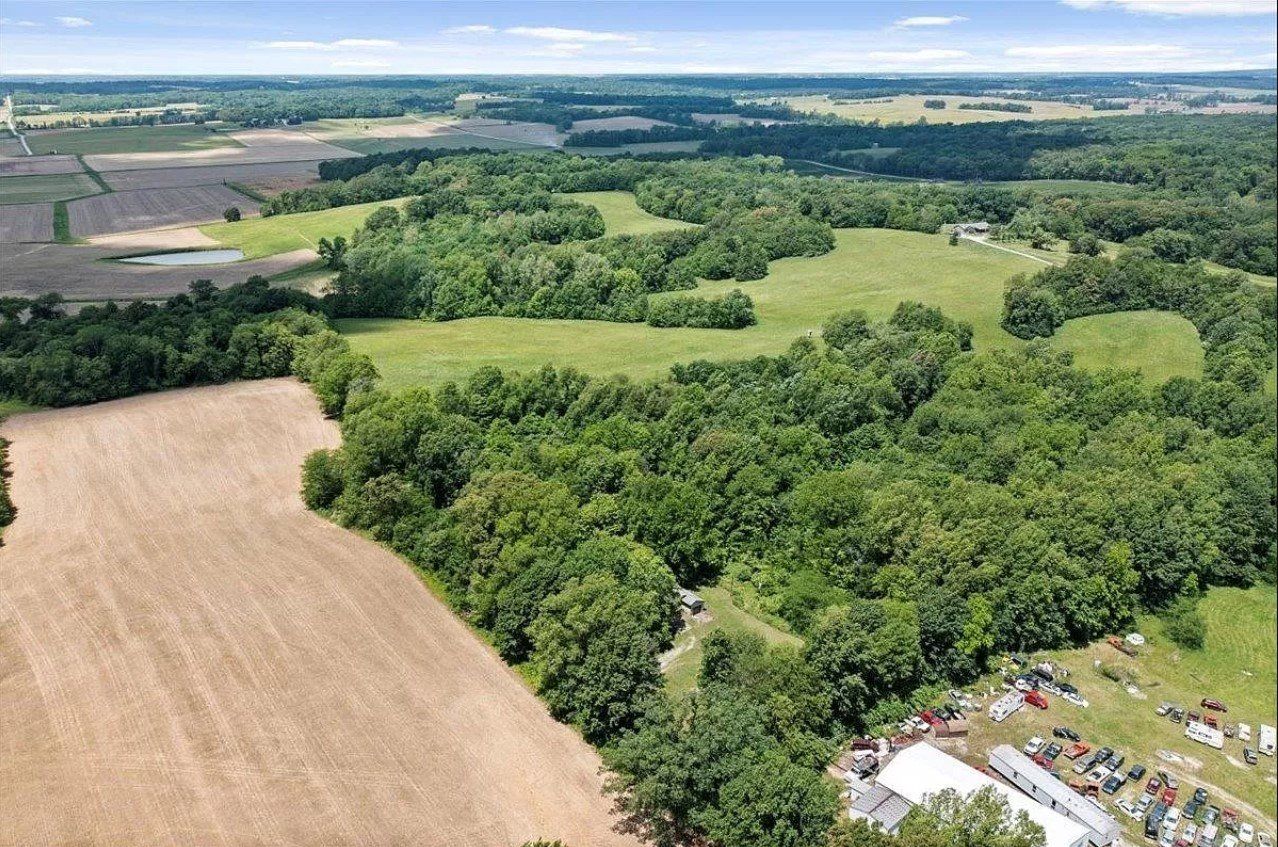 An aerial view of a lush green field surrounded by trees and fields.