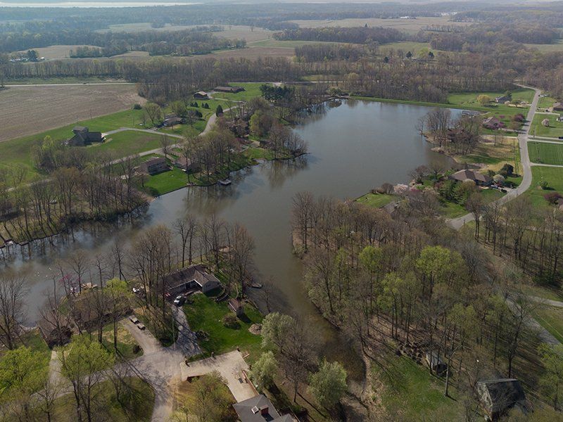 An aerial view of a lake surrounded by trees and fields.