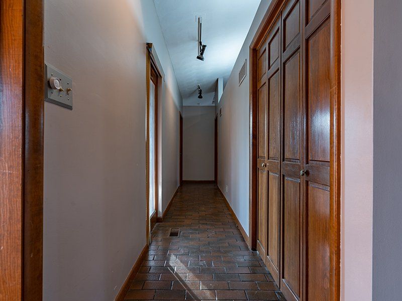 A long hallway with wooden doors and tile floors in a house.