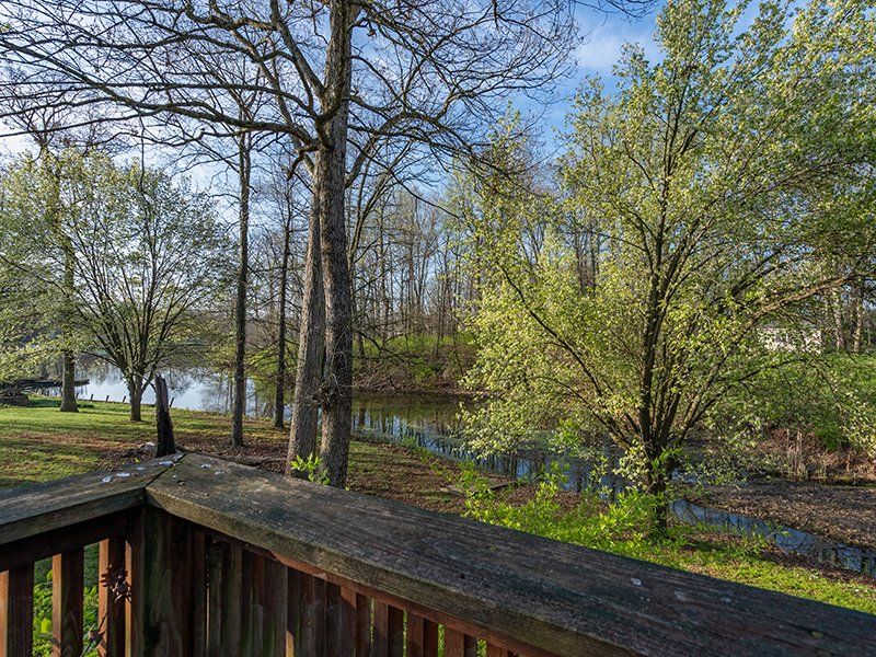 A wooden deck overlooking a river with trees in the background.