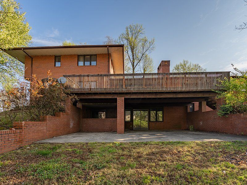 The back of a large brick house with a large deck.