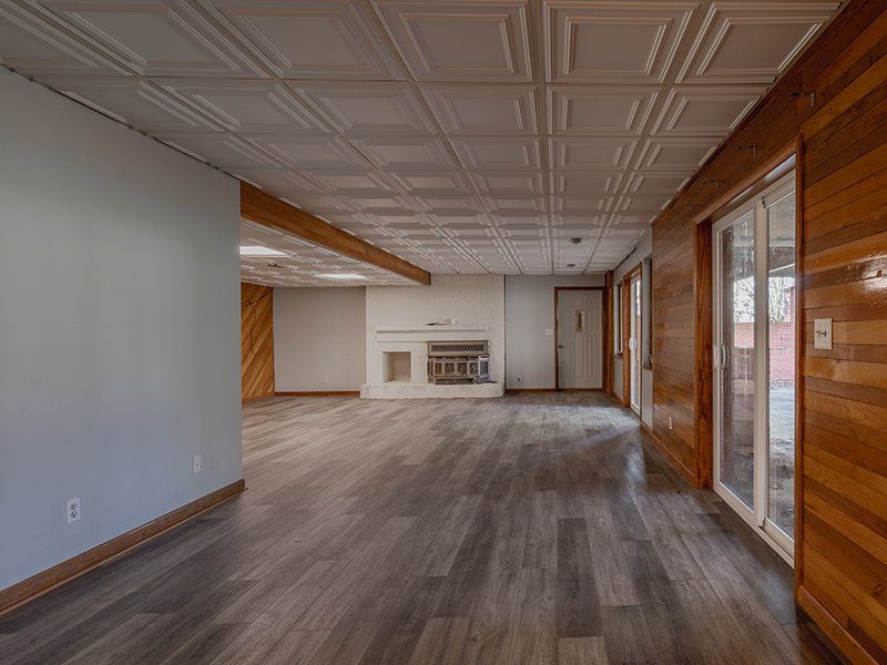 An empty basement with hardwood floors and a fireplace.