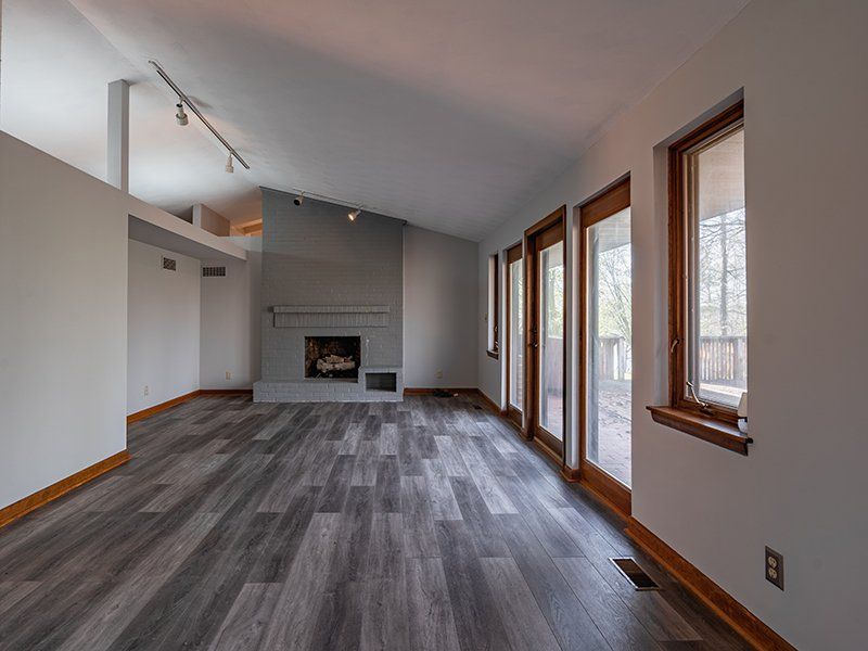 An empty living room with a fireplace and lots of windows.