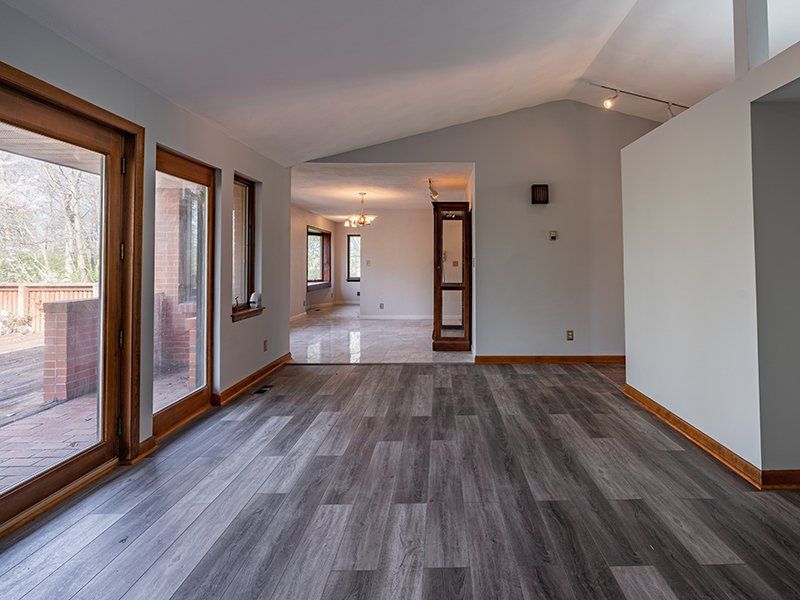 An empty living room with hardwood floors and lots of windows.