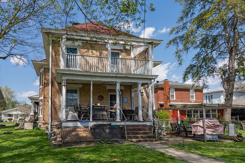 A large brick house with a large porch in a residential area.