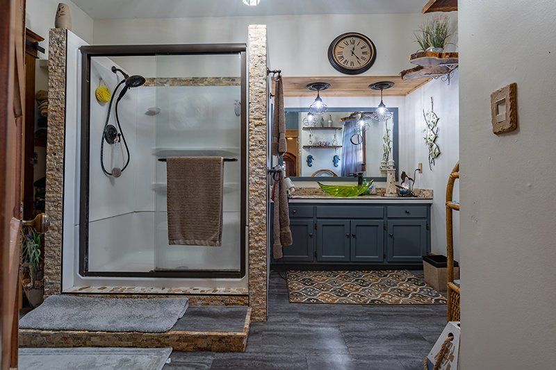 A bathroom with a walk in shower and a sink.
