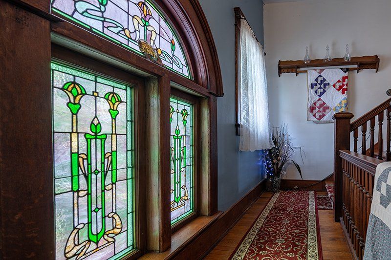 A hallway with stained glass windows and a staircase.