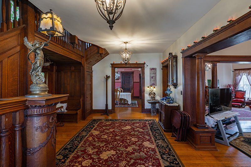 A large hallway in a house with a red rug and a statue of an angel.
