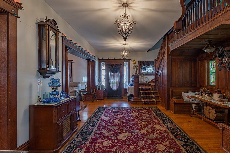 A large hallway in a house with a red rug and a chandelier.