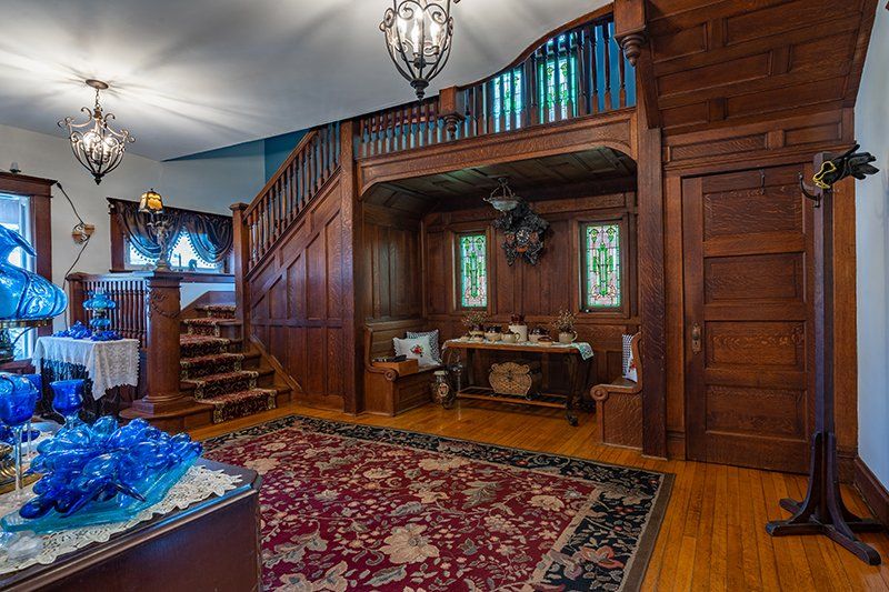 A living room with a wooden staircase and a rug.