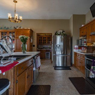 A kitchen with stainless steel appliances , wooden cabinets , a sink , and a refrigerator.