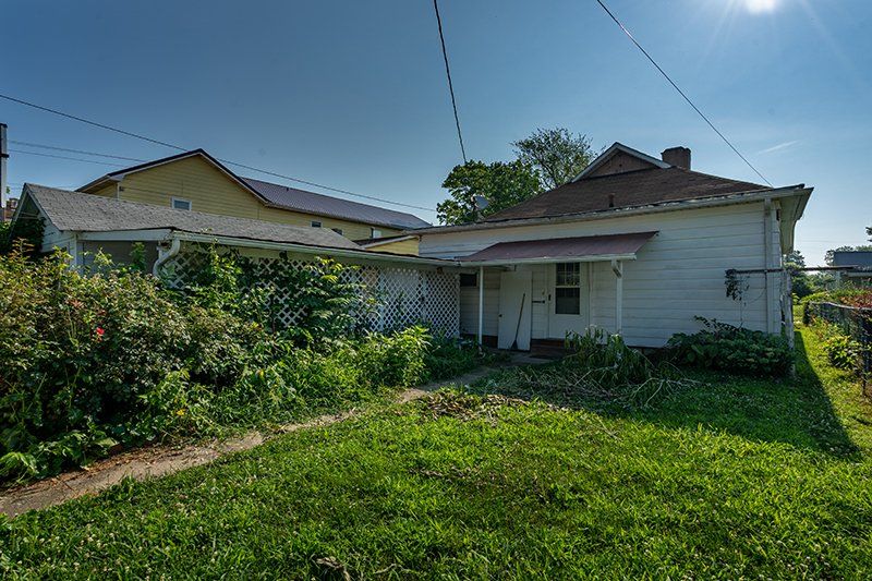 A white house with a porch and a lot of grass in front of it.