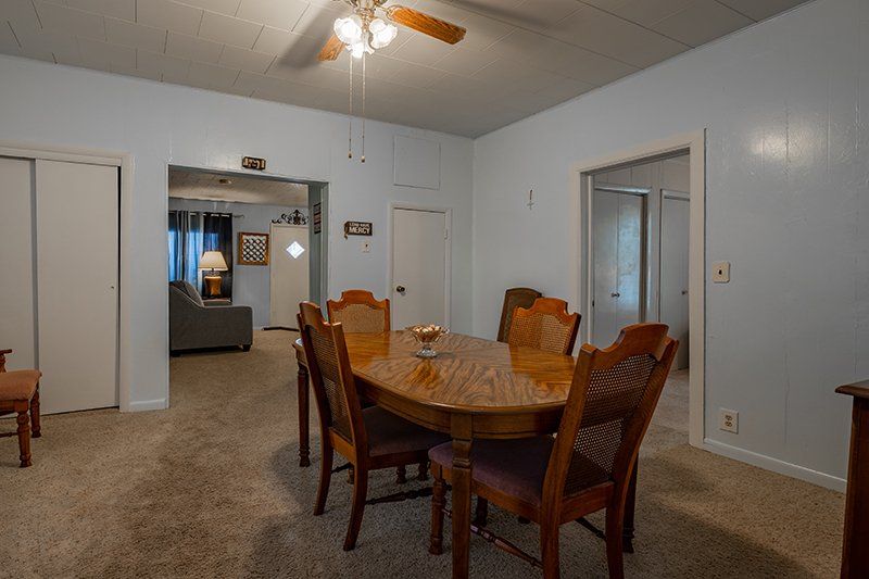 A dining room with a table and chairs and a ceiling fan.