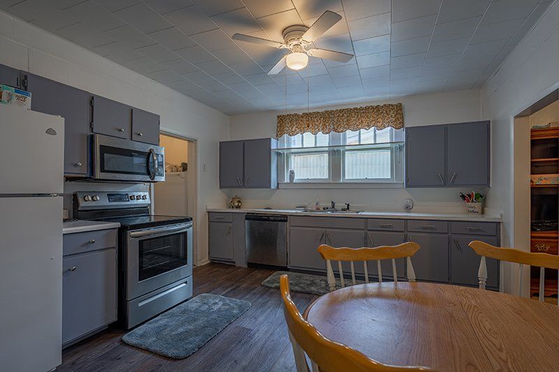 A kitchen with a table and chairs and a ceiling fan.