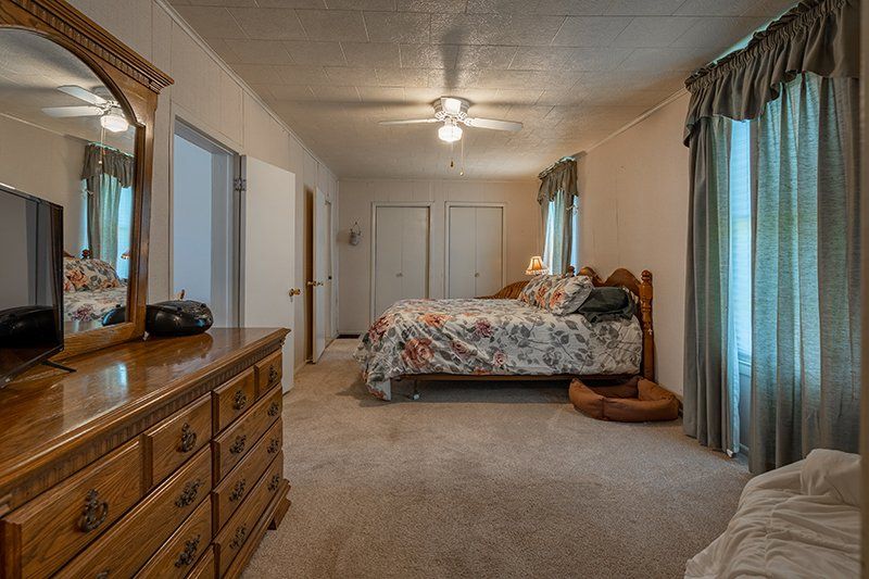 A bedroom with a bed , dresser , mirror and television.