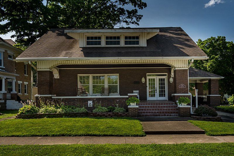 A large brick house with a lush green lawn in front of it.