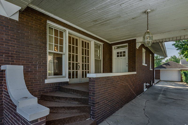 A brick house with a porch and stairs leading to the front door.