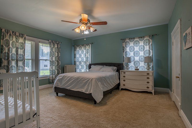 A bedroom with a bed , dresser , and ceiling fan.
