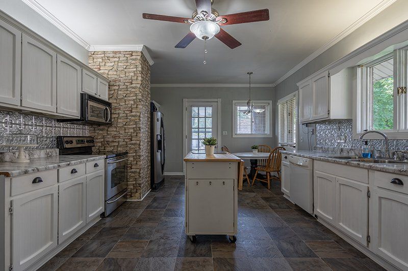 A kitchen with white cabinets and a ceiling fan.