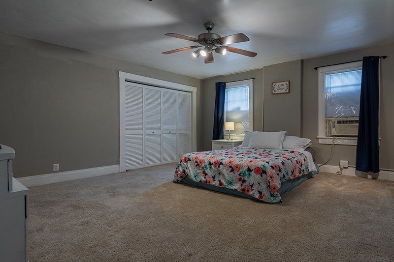 A bedroom with a bed and a ceiling fan.