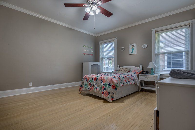 A bedroom with a bed and a ceiling fan.
