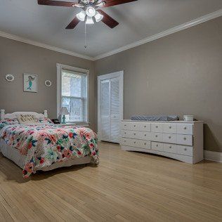 A bedroom with a bed , dresser , and ceiling fan.