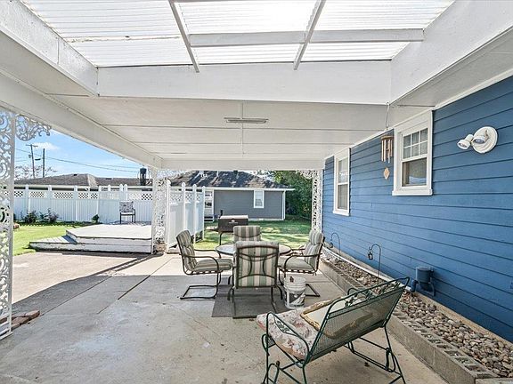 A blue house with a covered patio with a table and chairs.