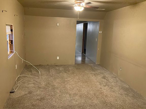 An empty living room with a ceiling fan and a window.