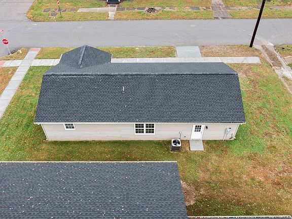 An aerial view of a house with a black roof in a residential area.