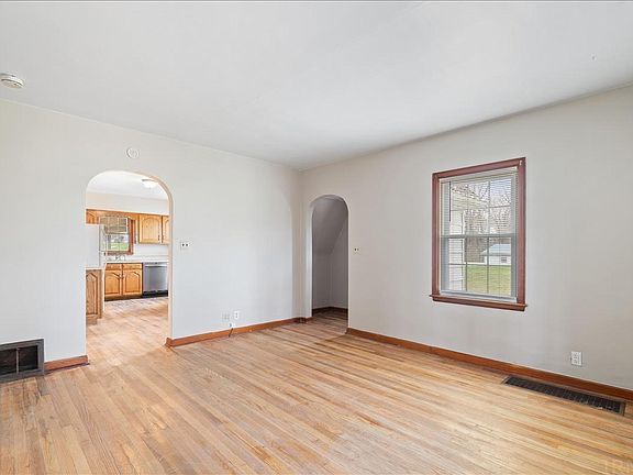 An empty living room with hardwood floors and two windows.