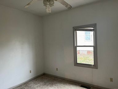 An empty bedroom with a ceiling fan and a window.