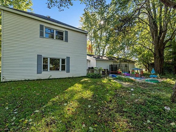 The backyard of a house with a lot of grass and trees.