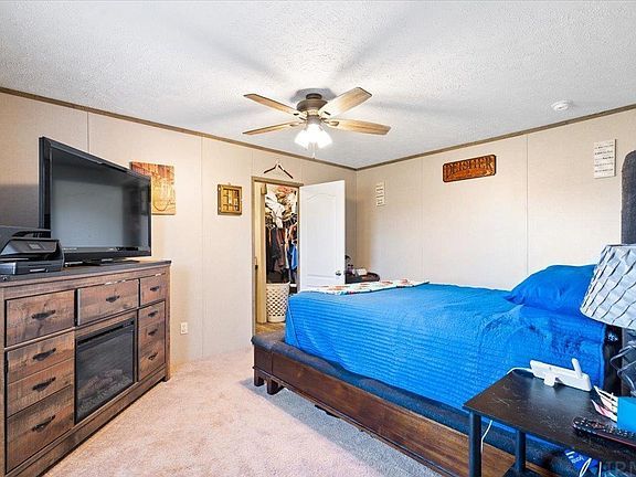 A bedroom with a bed , television , fireplace and ceiling fan.