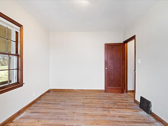 An empty room with wooden floors and two windows