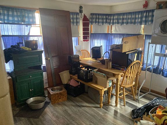 A room with a table and chairs and a dog bowl on the floor.