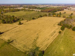 An aerial view of a large field with trees in the background.