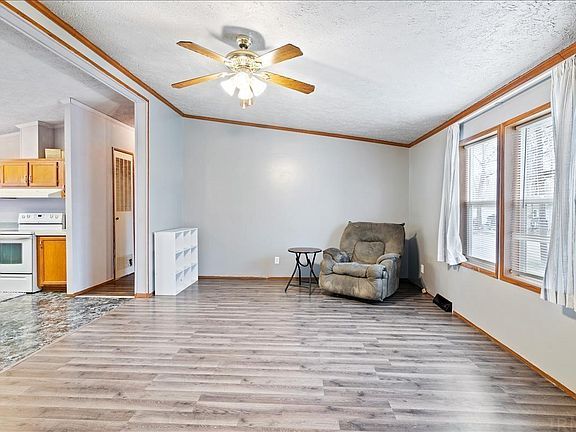 An empty living room with a chair and a ceiling fan