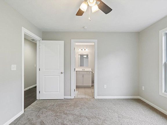 An empty bedroom with a ceiling fan and a bathroom.