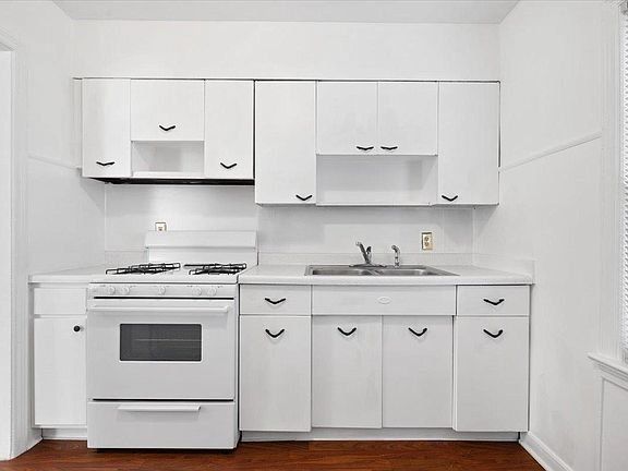 A kitchen with white cabinets and a white stove