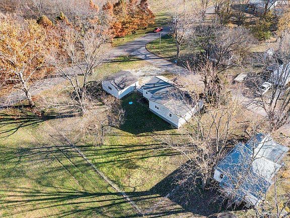 An aerial view of a house surrounded by trees and grass.