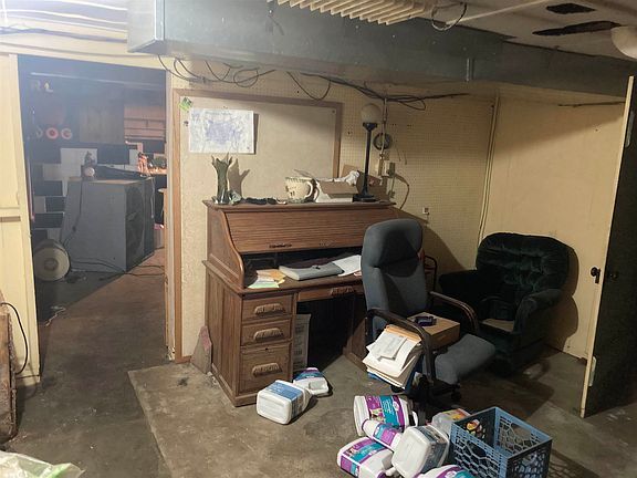 A messy room with a desk , chair , and toilet paper.