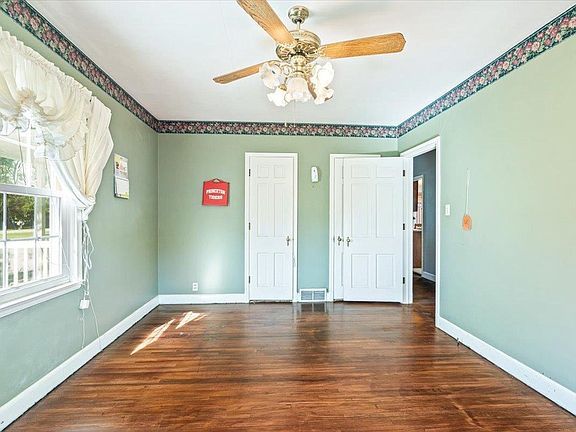 An empty room with hardwood floors and a ceiling fan.