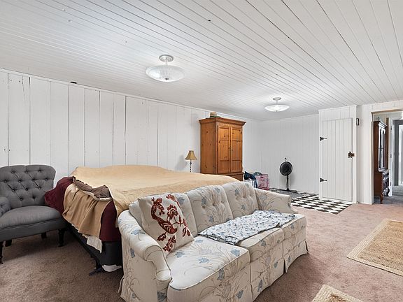 A living room with a couch , chair , and bed.