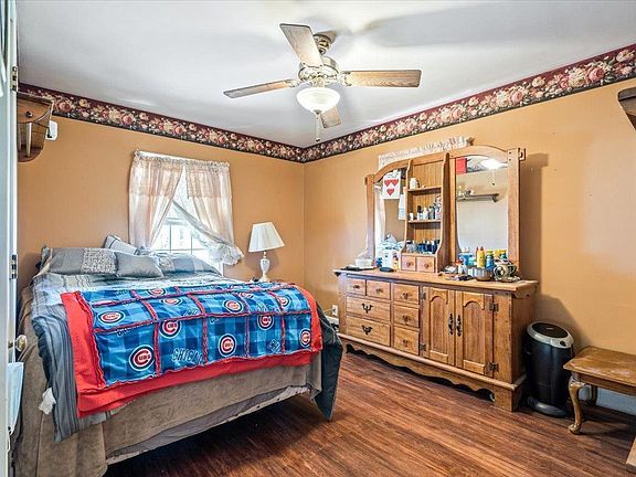 A bedroom with a bed , dresser , mirror and ceiling fan.