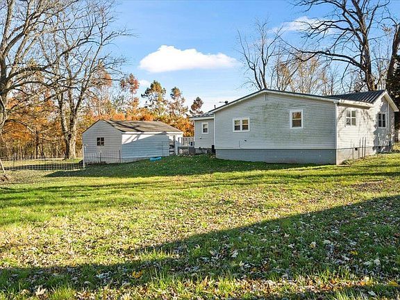 A mobile home is sitting in the middle of a grassy field.