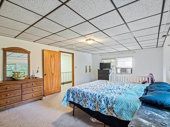 A bedroom with a bed , dresser , mirror and television.